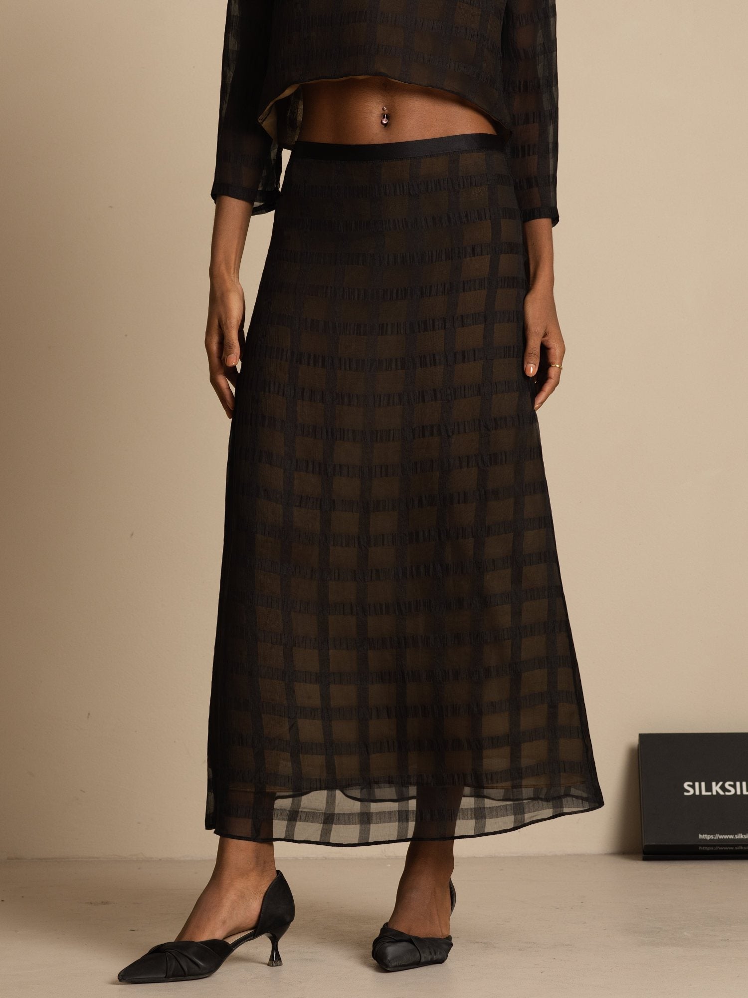 High-waist black silk A-line skirt with textured grid pattern and tea-length silhouette