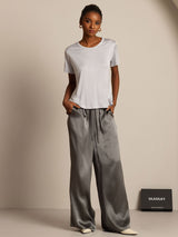 Model wearing white crew neck Silk Jersey T-shirt with gray wide-leg silk pants