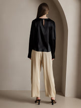 Black silk long sleeve boat neck blouse with back keyhole detail and beige pants