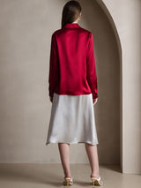 Back view of a woman wearing a red silk long-sleeve lapel shirt with a white skirt