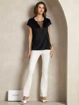 Black silk cap sleeve top with sheer V insert, styled with white pants