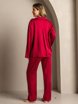 Back view of a woman wearing a red long sleeve silk pajama set with relaxed fit pants