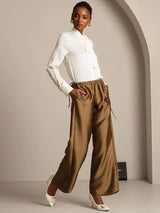 Woman wearing silk-wool straight-leg pants with drawstring side pockets, cream blouse