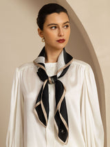Black and beige silk square scarf tied at the neck over a white blouse