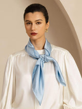 Light blue 100% mulberry silk square scarf tied at the neck over a white blouse
