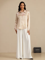 Beige silk lapel blouse with crane print and button front, shown with white wide-leg pants