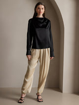 Black silk long sleeve boat neck blouse with pearl cuffs, styled with beige pants