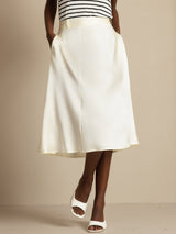 Ivory high-waist silk A-line midi skirt with pockets, worn with white slide sandals