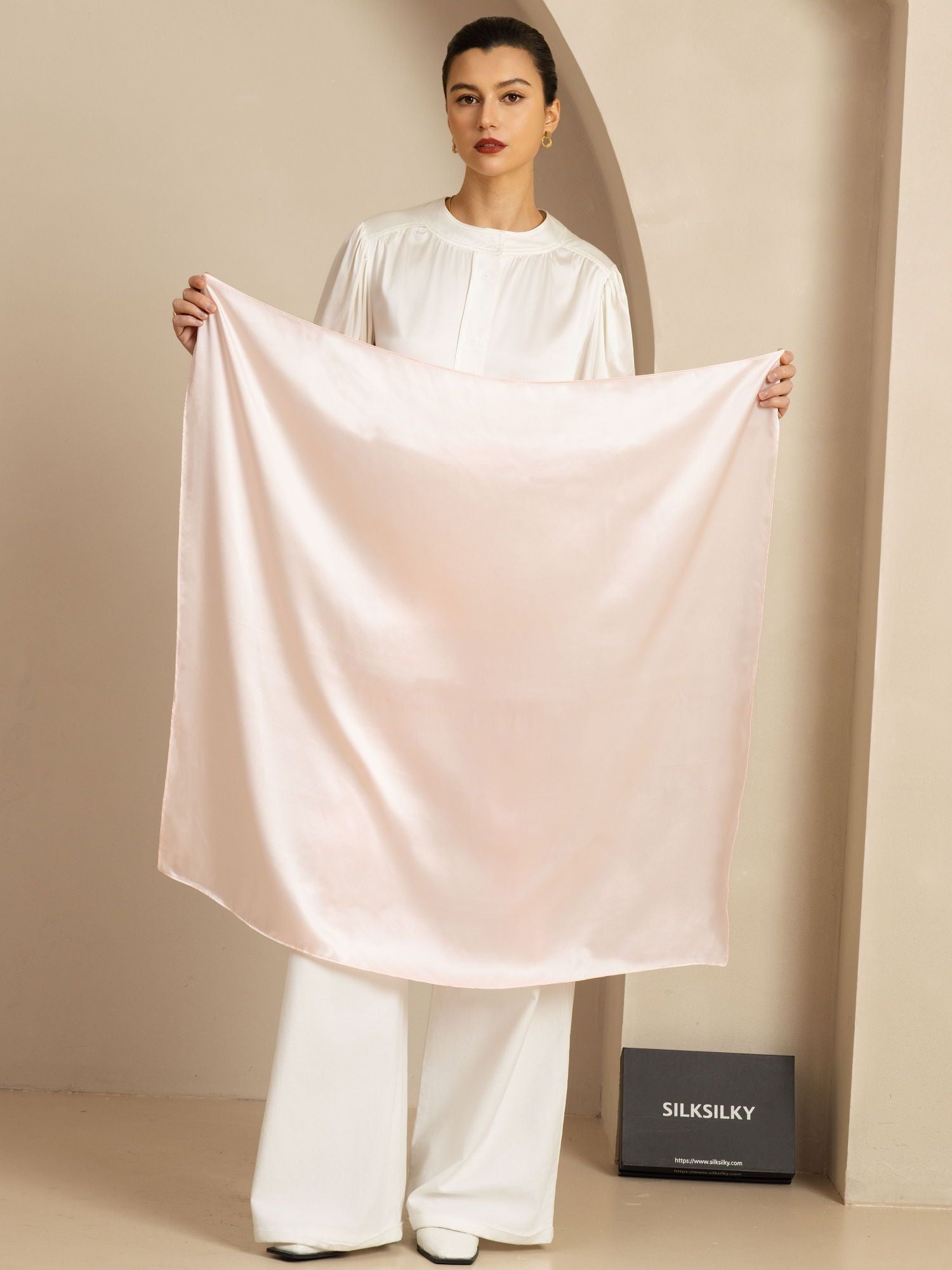 Woman holding a pale pink 100% mulberry silk square scarf, 90x90cm