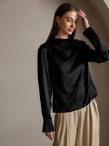 Black silk long sleeve boat neck blouse with pearl cuffs and beige trousers