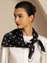 Black Mulberry silk square scarf with white paw prints, styled around the neck