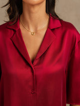 Woman wearing a red silk notch collar pajama top with button front