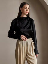 Black long sleeve silk blouse with curved neckline and beige wide-leg pants