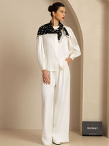 Woman wearing a white silk pajama set with a black paw print scarf