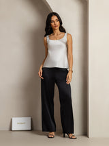 Woman wearing a white sleeveless U-neck silk tank top with black pants